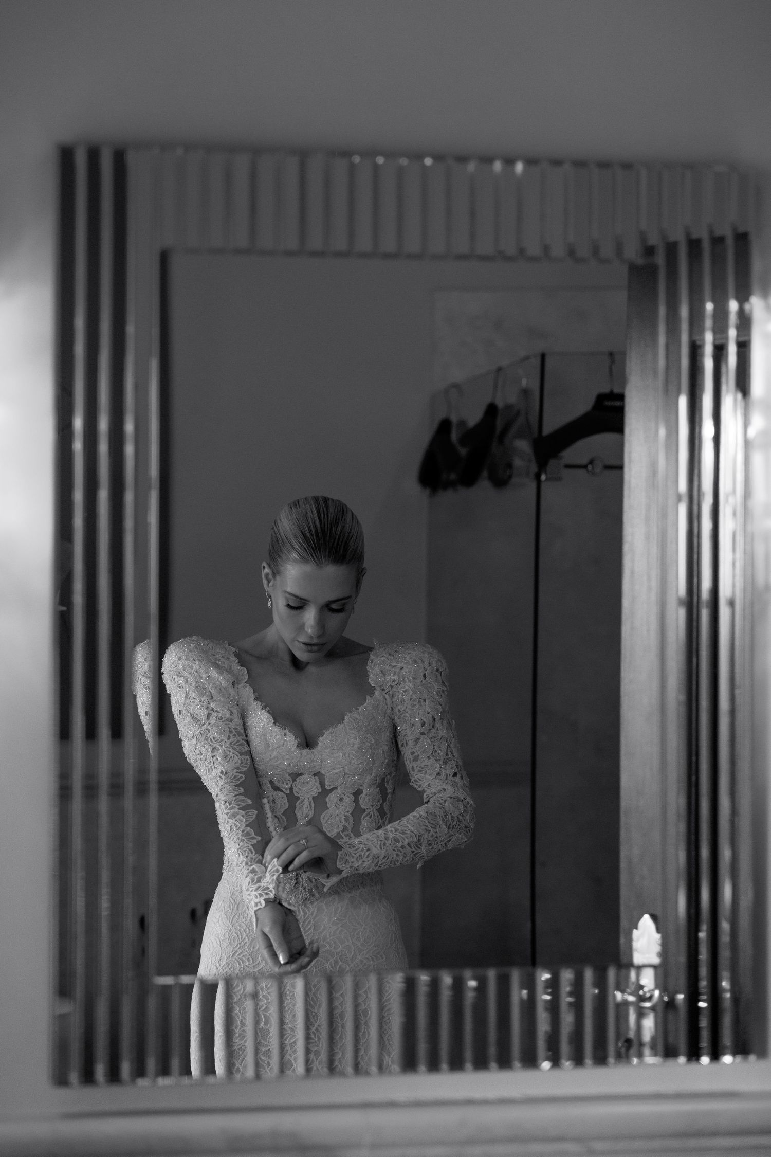 A reflection in mirrors shows someone adjusting a white lace dress.