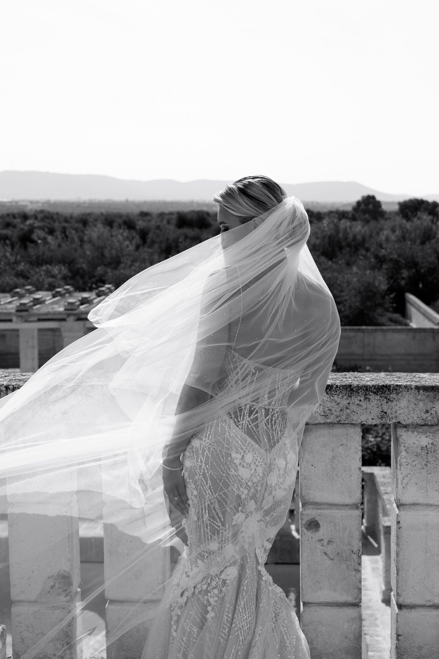 Flowing white wedding veil billowing in the wind against a bright sky.
