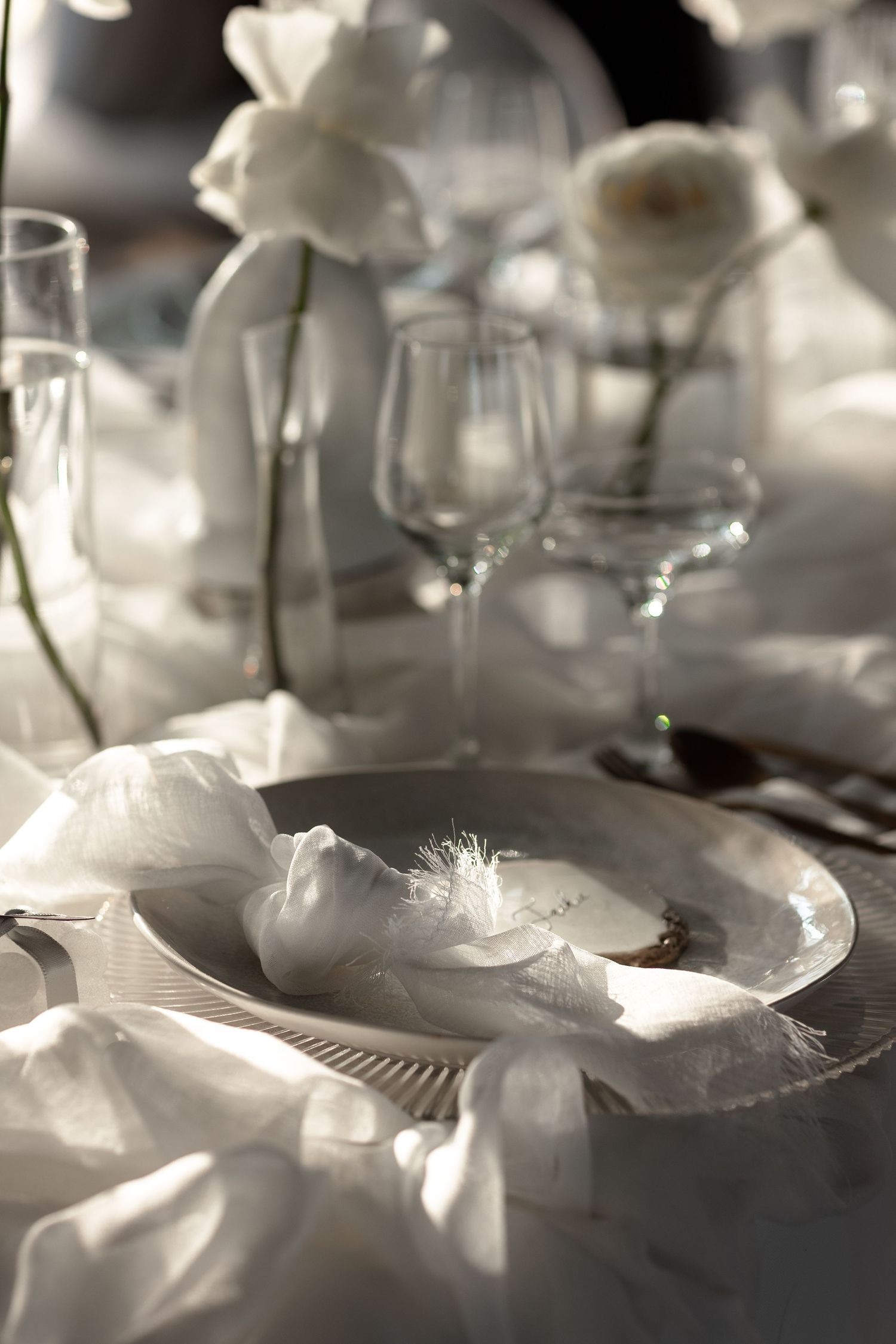 Delicate white feathers and decorative elements create an ethereal table setting in soft focus.