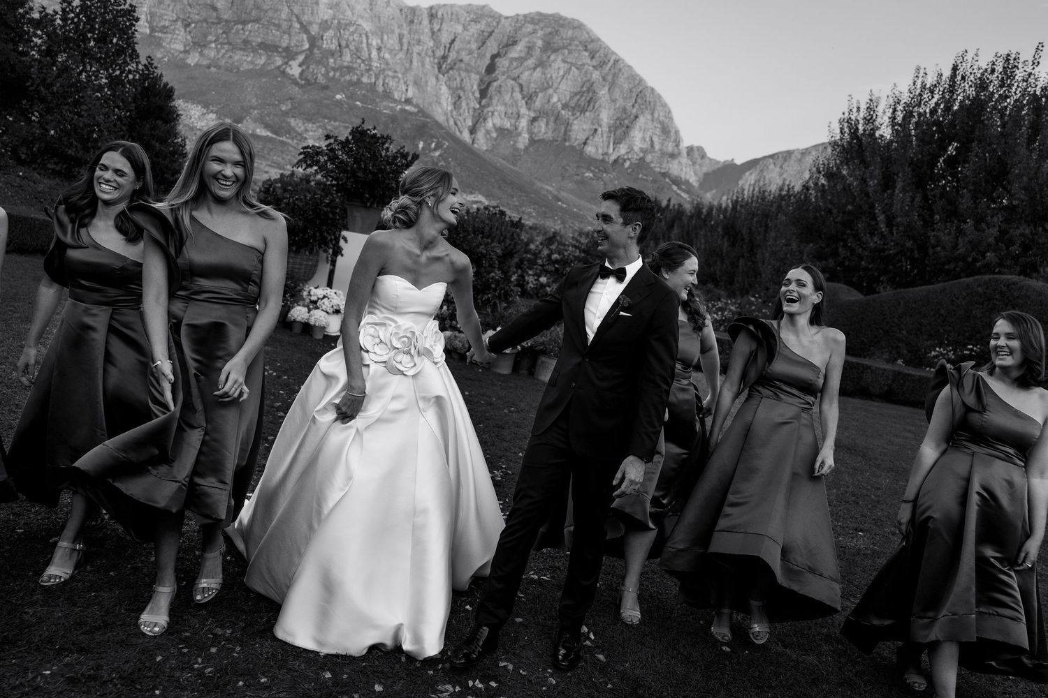 Wedding party poses together against mountain backdrop.