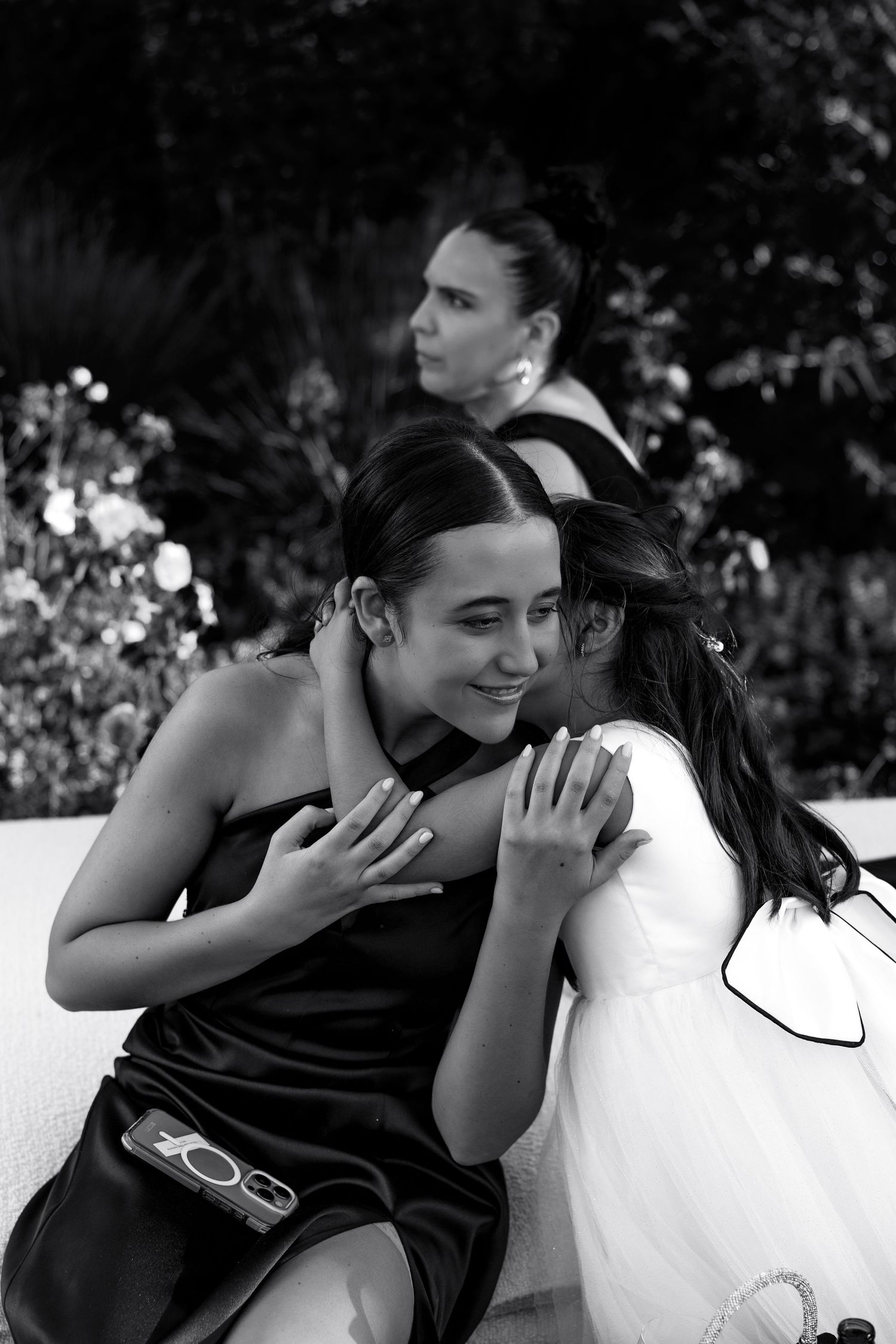 A black and white photo series shows a couple embracing and sharing intimate moments in an outdoor garden setting.