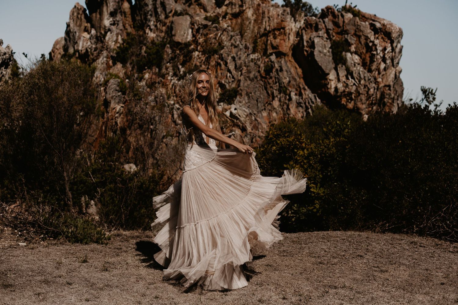 A flowing dress twirls dramatically against a rocky mountain backdrop during sunset.