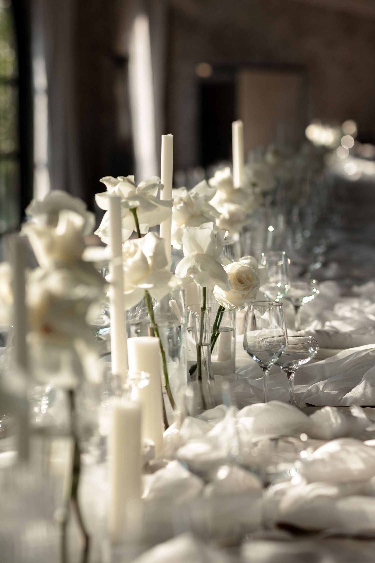 Romantic wedding table setting with white flowers, candles and delicate linens.