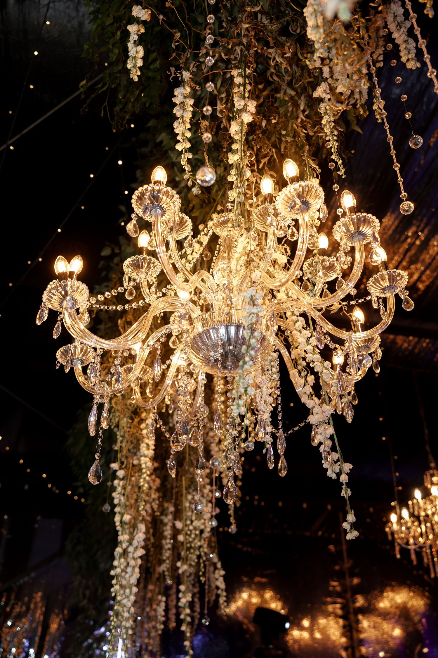 Crystal chandeliers sparkle with warm light against a dark background, creating an elegant and romantic atmosphere.