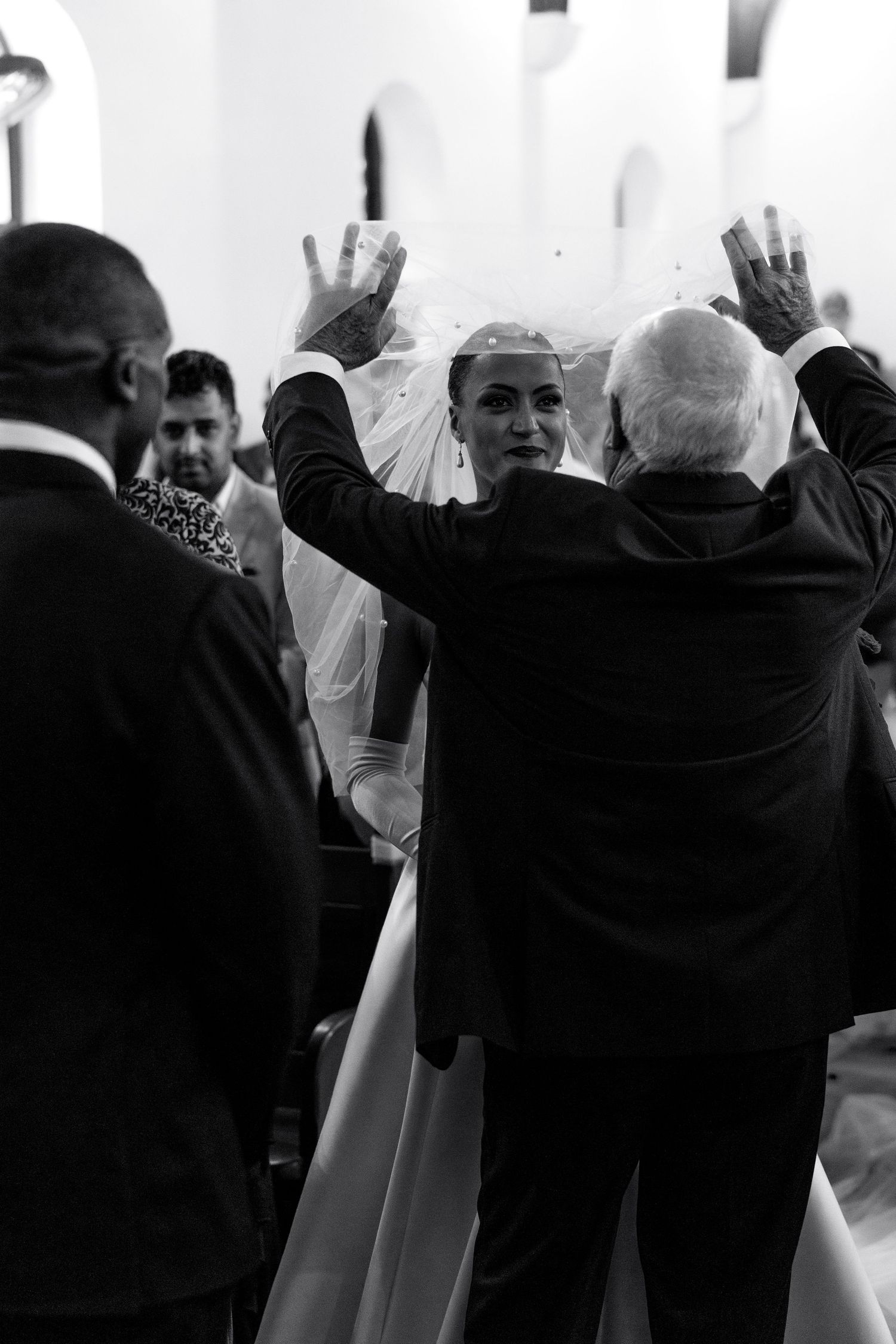 A black and white photo of a wedding ceremony with people raising their hands in blessing or prayer.