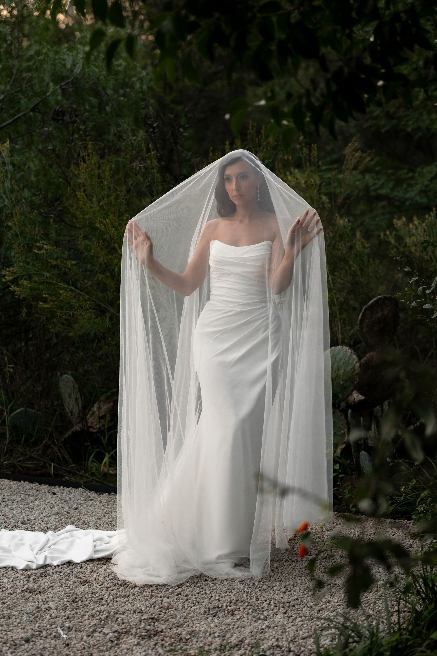 White wedding dress and veil creating dramatic silhouettes against natural outdoor backdrop.