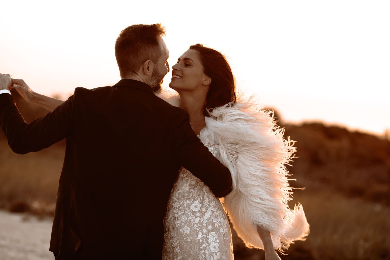A romantic dance between newlyweds backlit by golden sunset light.