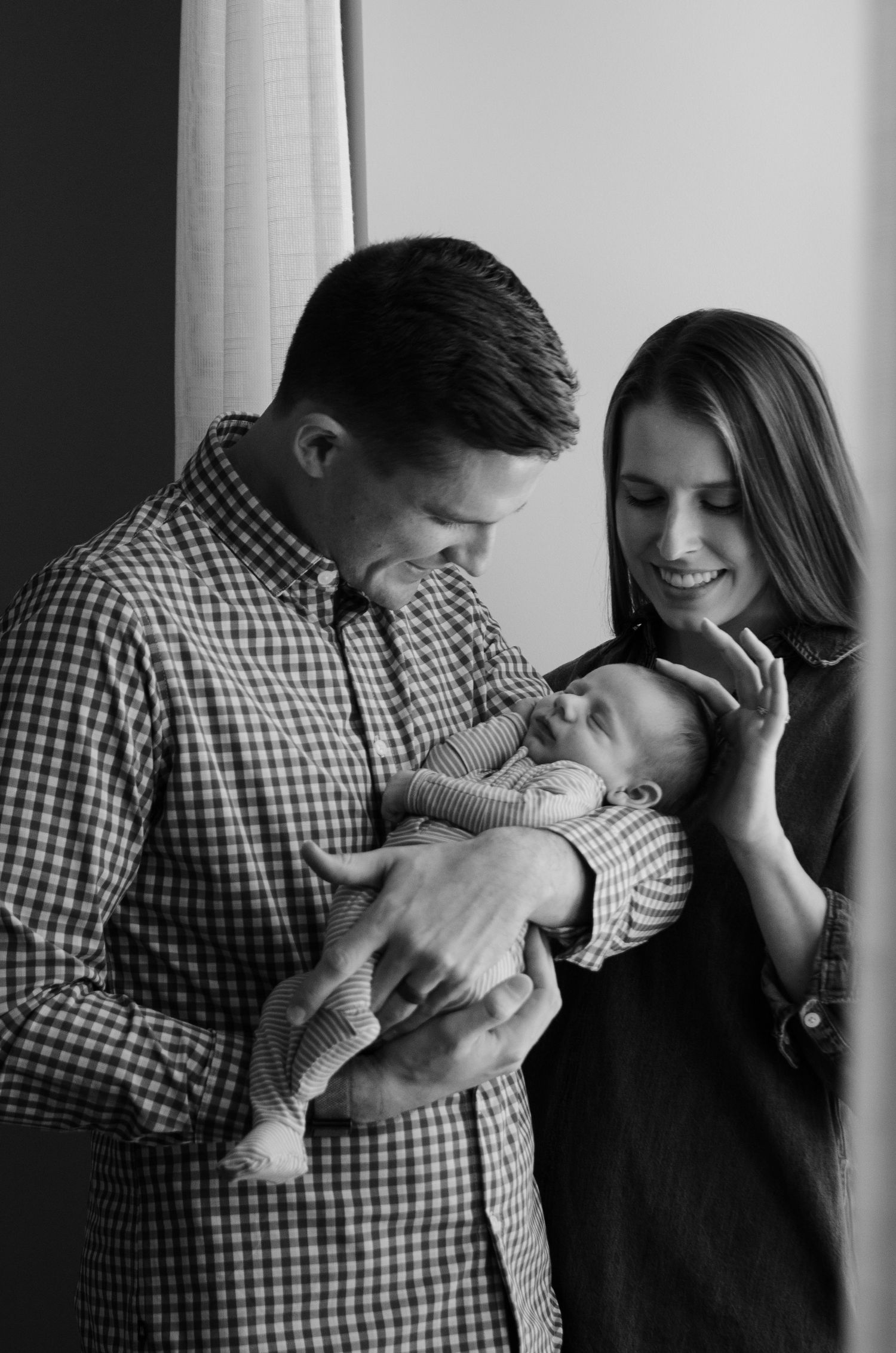Black and white family portrait with a sleeping baby during a lifestyle newborn photography session in Charlotte, NC.