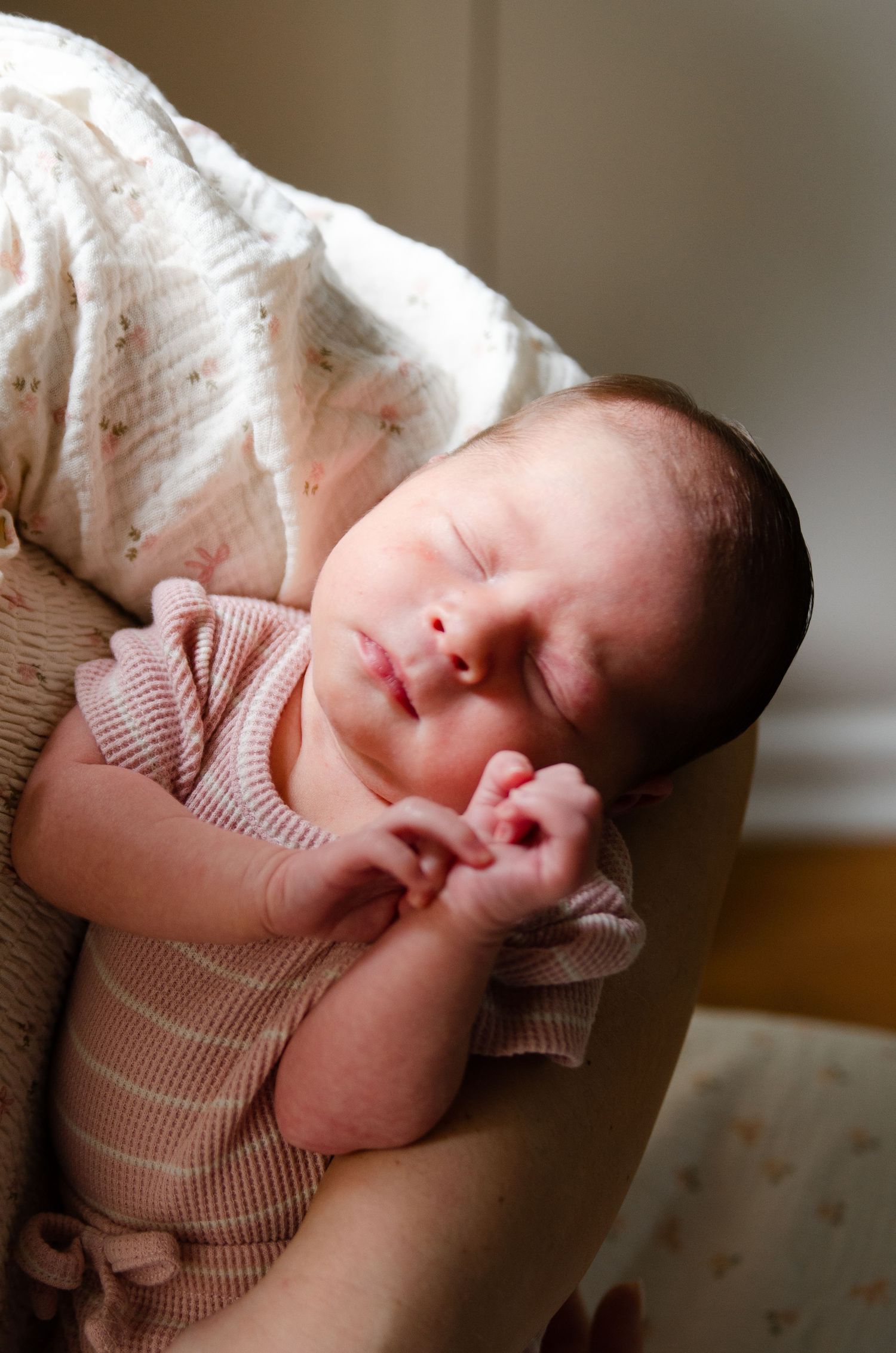 A sleeping baby in a pink knit sweater rests peacefully in a series of four connected photos.