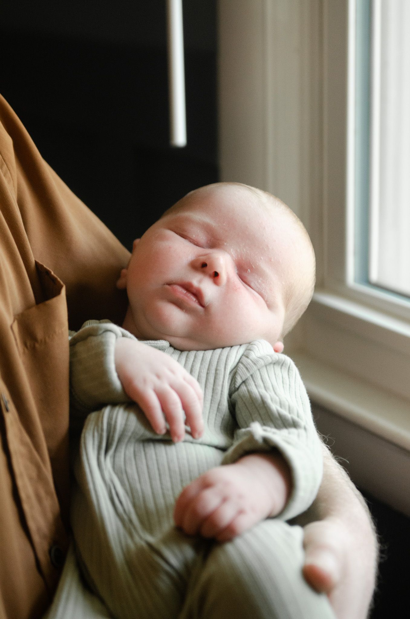 Sleeping baby photographed by a window during an in-home lifestyle newborn session in Charlotte, NC.