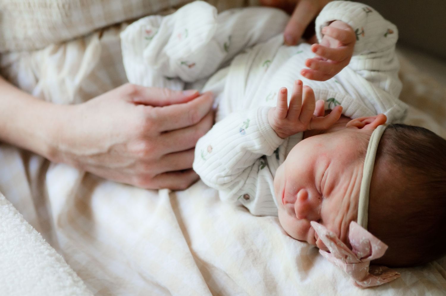 Newborn wrapped in a white blanket being cradled during a lifestyle newborn photography session in Charlotte, NC.