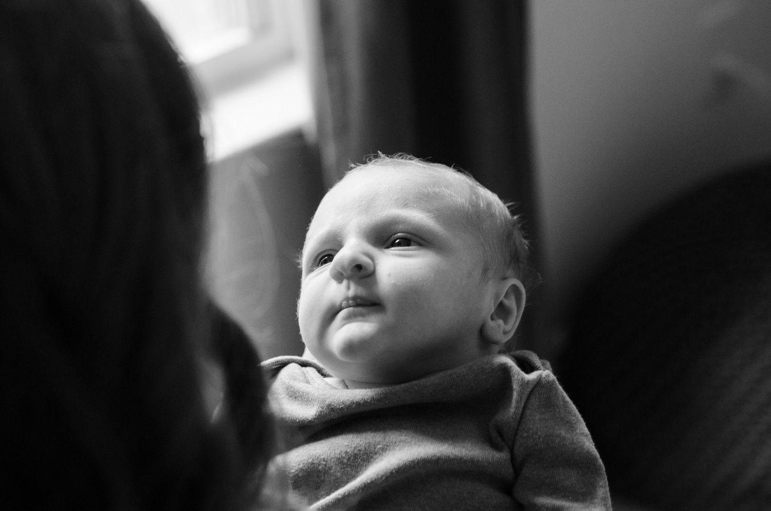 Black and white portrait of a baby looking up during a lifestyle newborn photography session in Charlotte, NC.