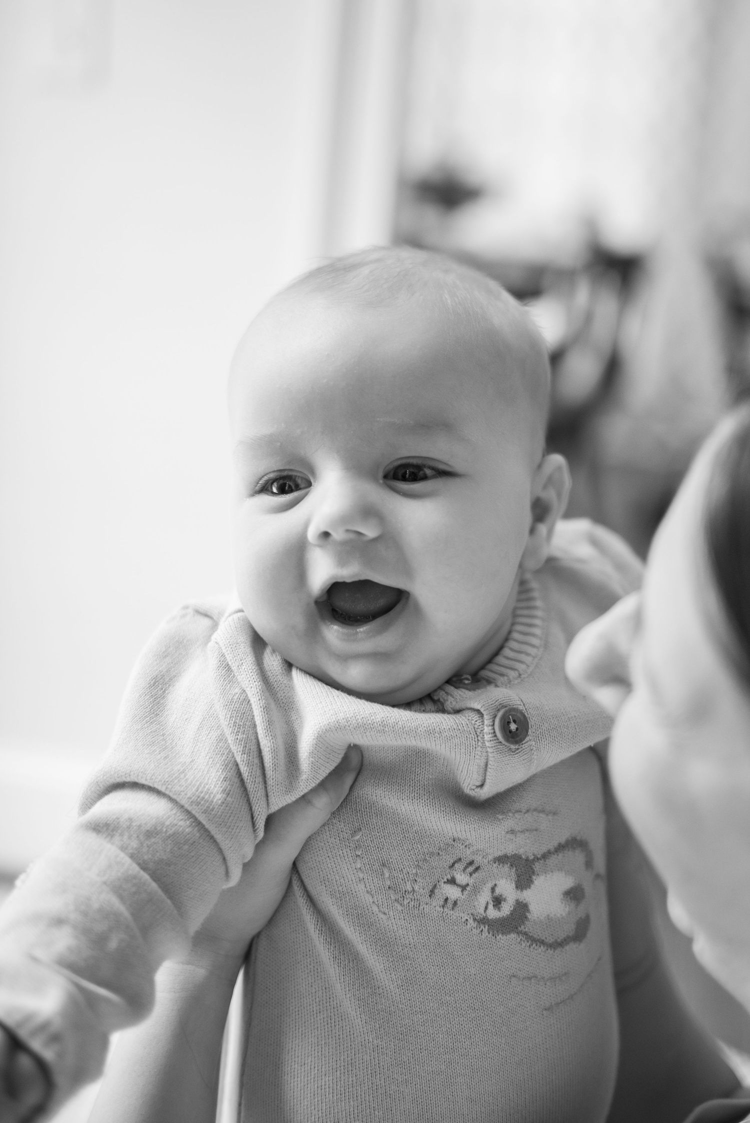 Black and white portrait of a smiling baby in a knit sweater during a lifestyle newborn photography session in Charlotte, NC.