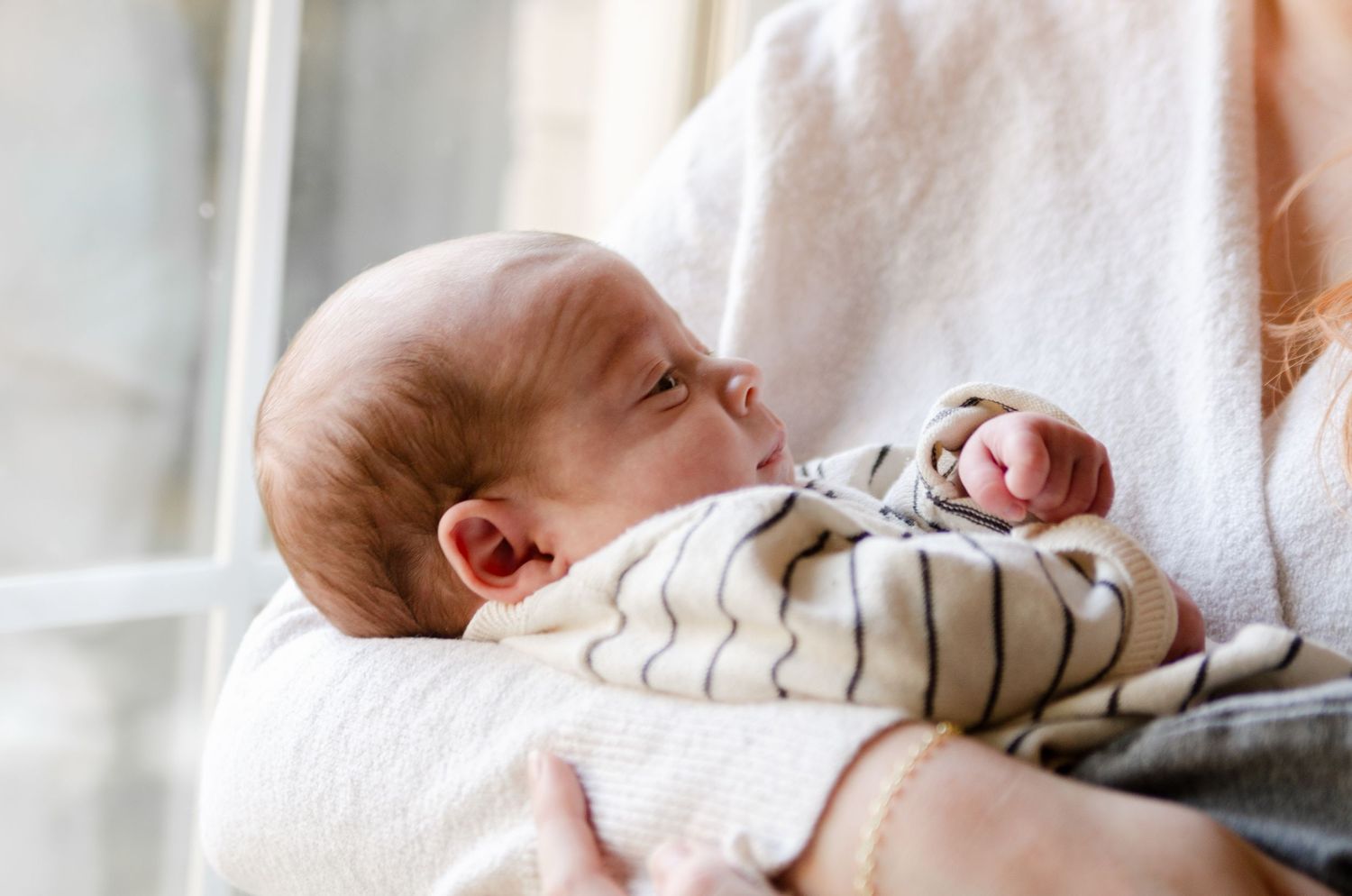 Sleepy baby resting against white fabric during a lifestyle newborn photography session in Charlotte, NC.