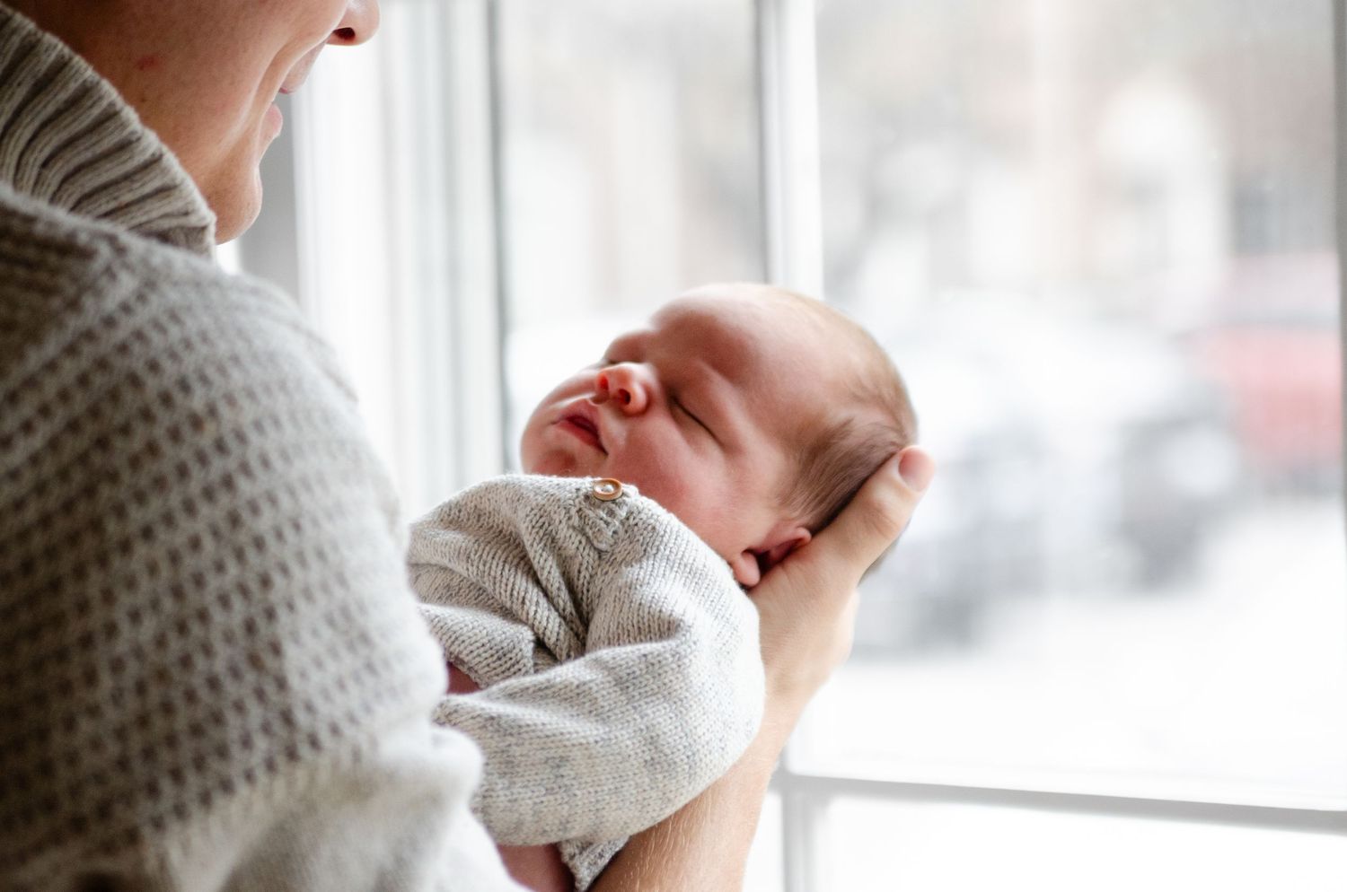 Gentle moments captured by a bright window during a lifestyle newborn photography session in Charlotte, NC.