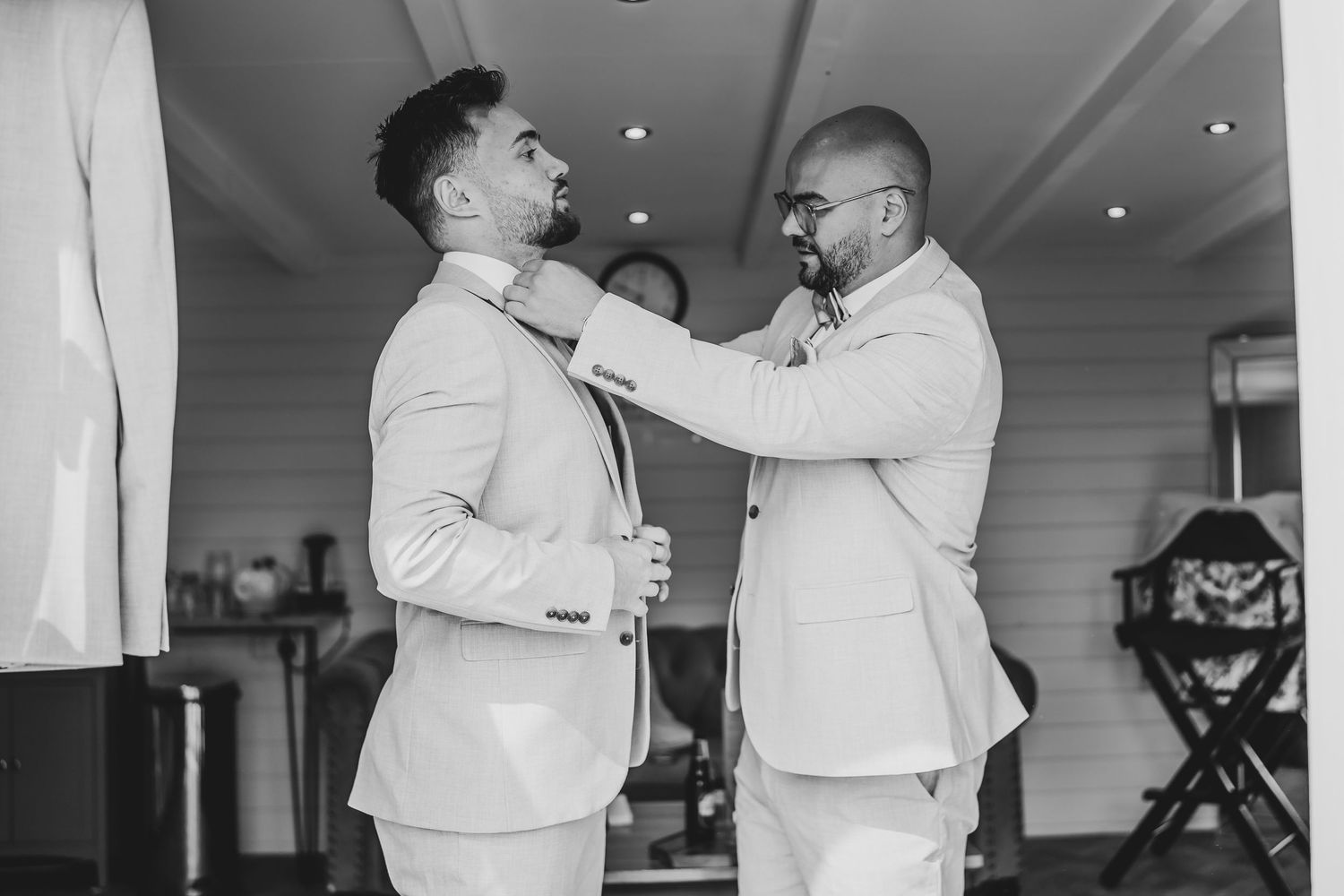 Wedding party members helping each other get dressed in formal attire.
