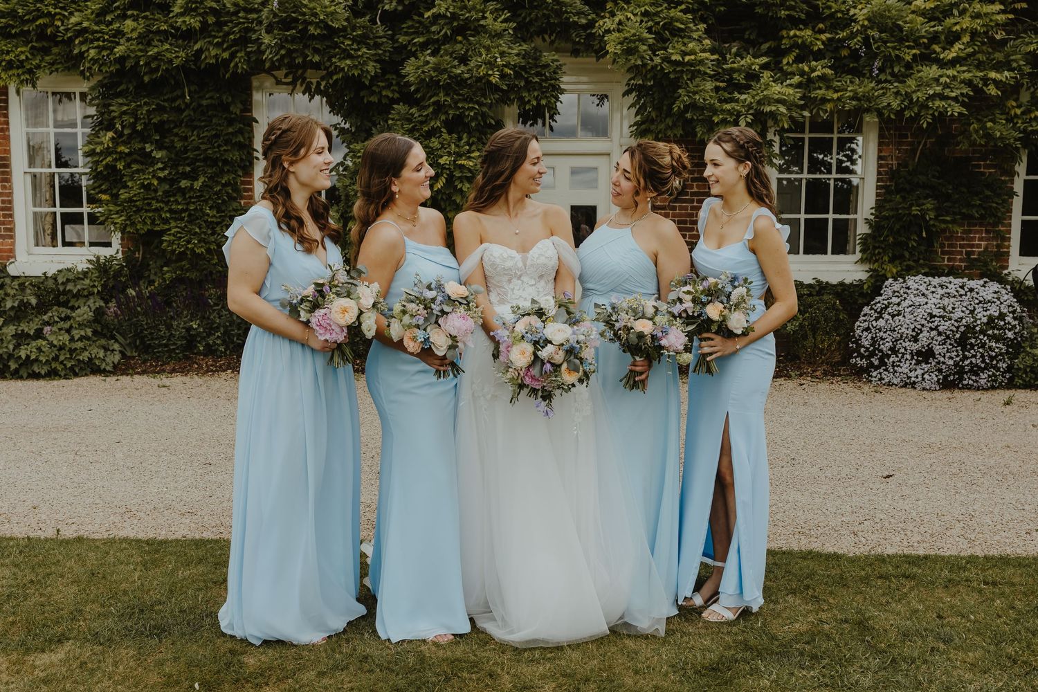 Wedding party in light blue dresses and white gown posing outdoors.