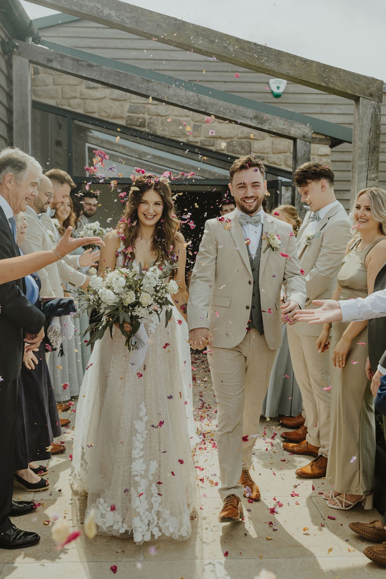 Newlyweds walk through shower of flower petals during their wedding exit.