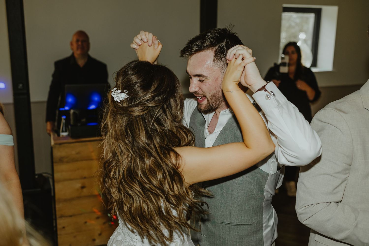 Wedding celebration with guests dancing in a rustic venue with wooden accents.
