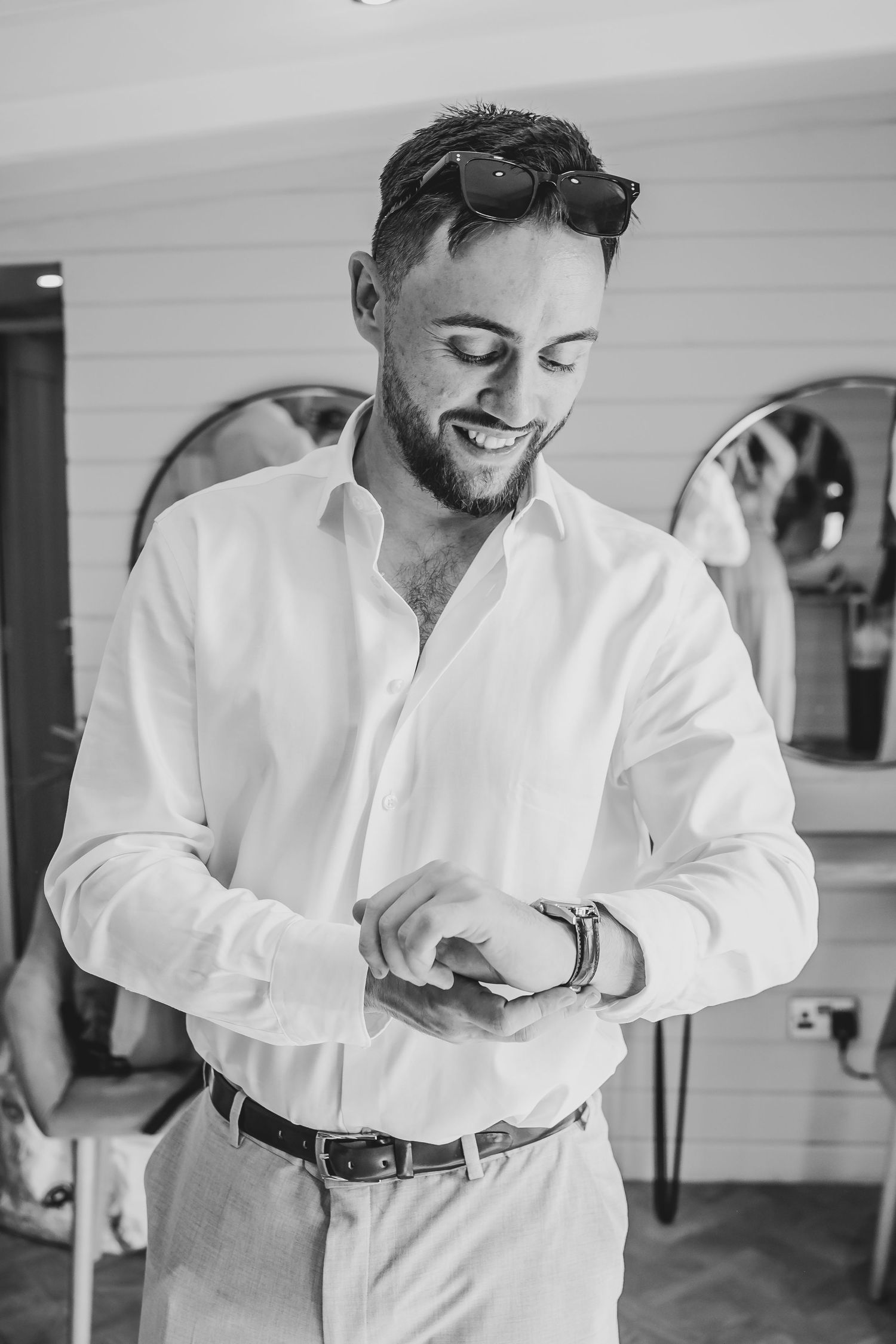 Person in white dress shirt adjusting cuffs while getting ready indoors.