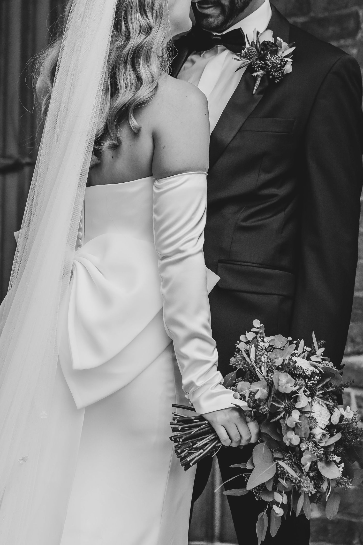 Elegant black and white portrait of couple in wedding attire with floral bouquet.