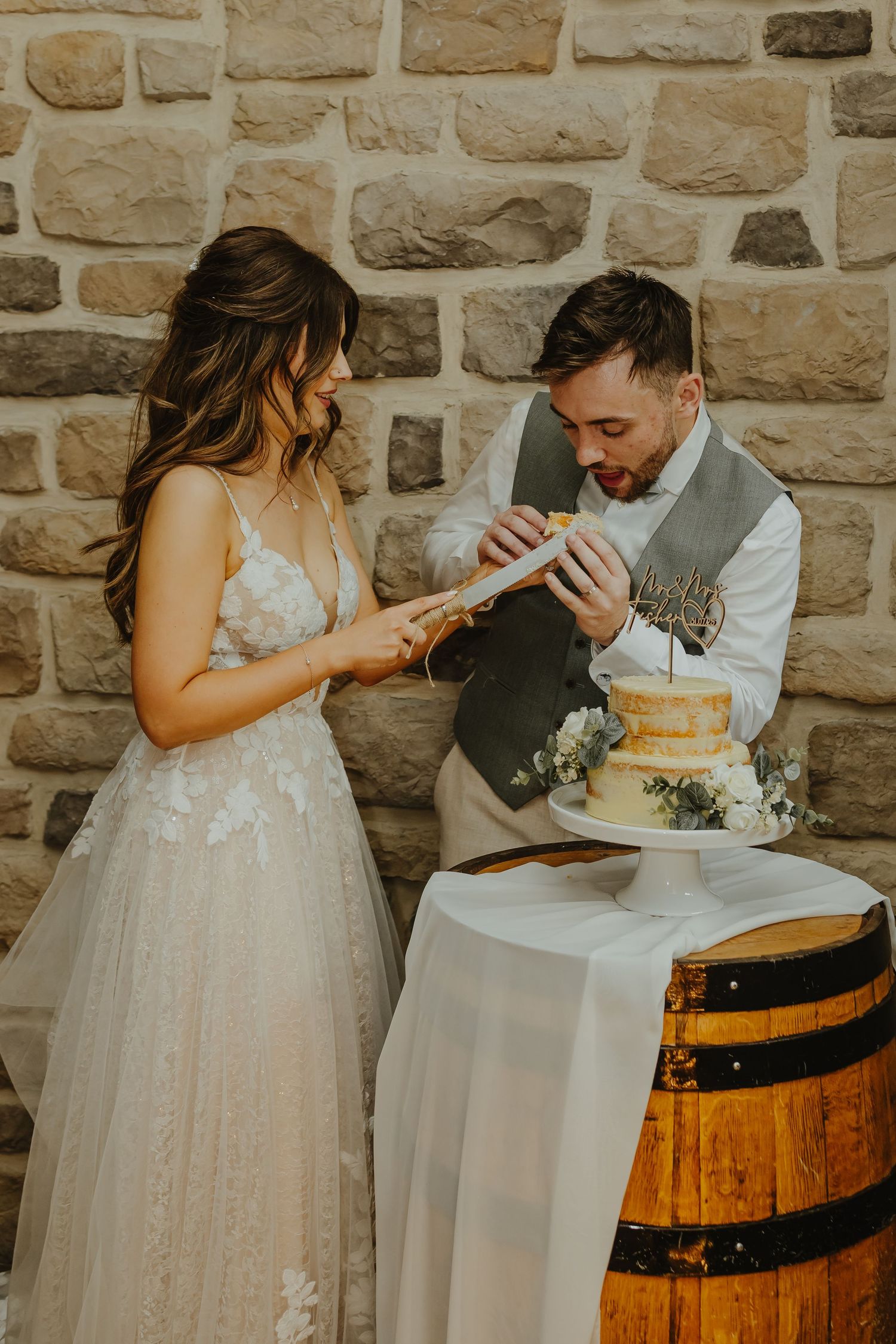 A couple cutting their wedding cake together on a rustic barrel display.