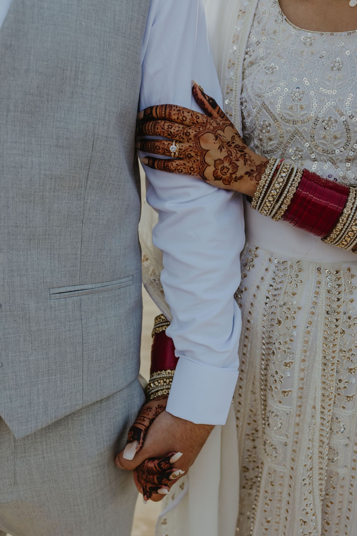 Detail shots of traditional henna designs on hands with white dress fabric.
