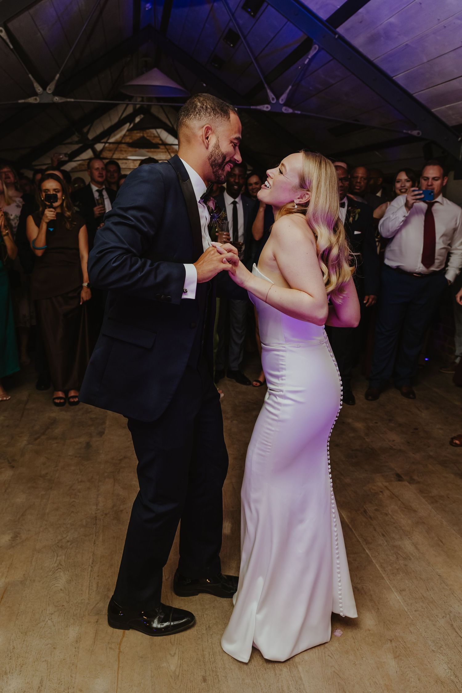 A couple laughs together during their first dance at a wedding reception.