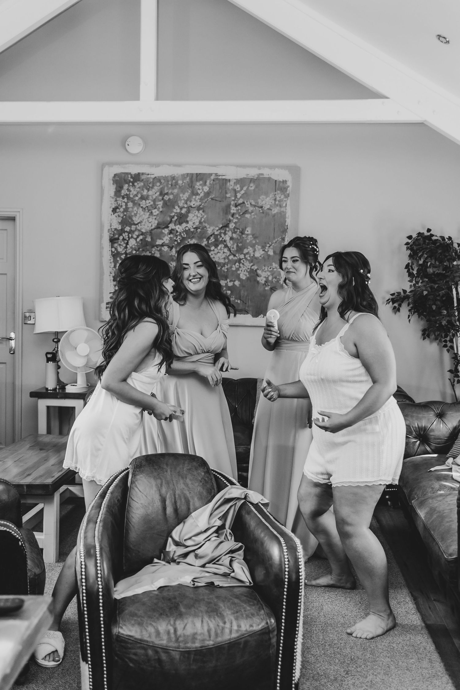 Group enjoying candid moments on a leather couch during wedding preparations.