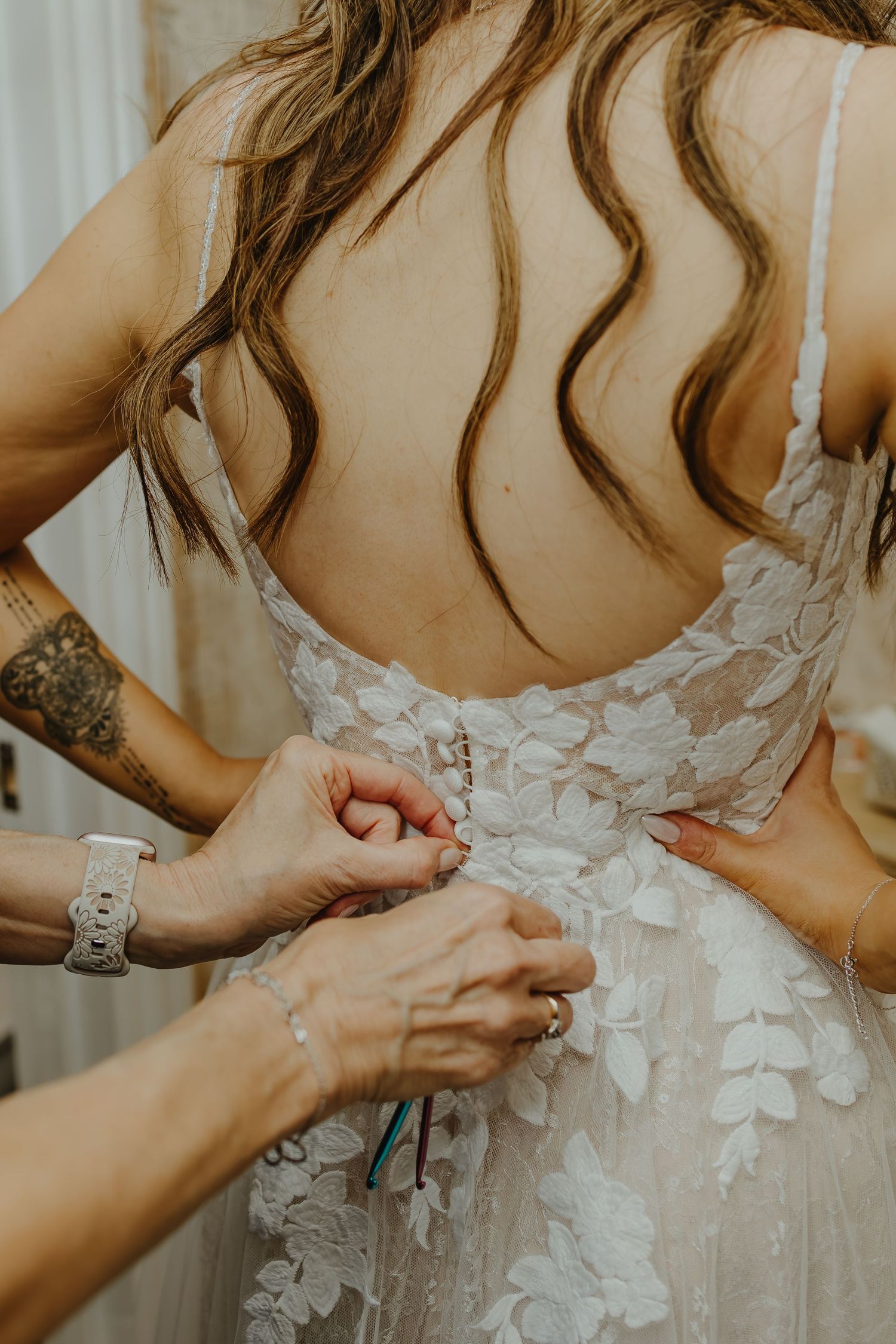 Detailed view of lace wedding dress being buttoned up.