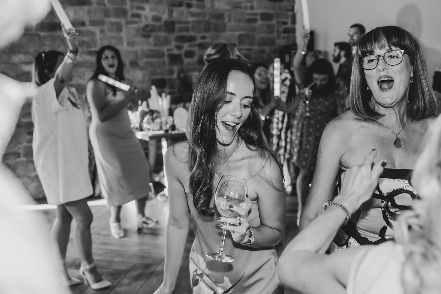 Black and white photo of wedding guests dancing and celebrating at a reception.
