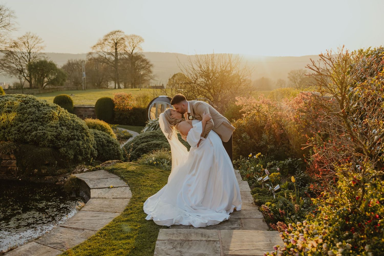 Sunset wedding portrait with couple on stone path surrounded by autumn foliage.