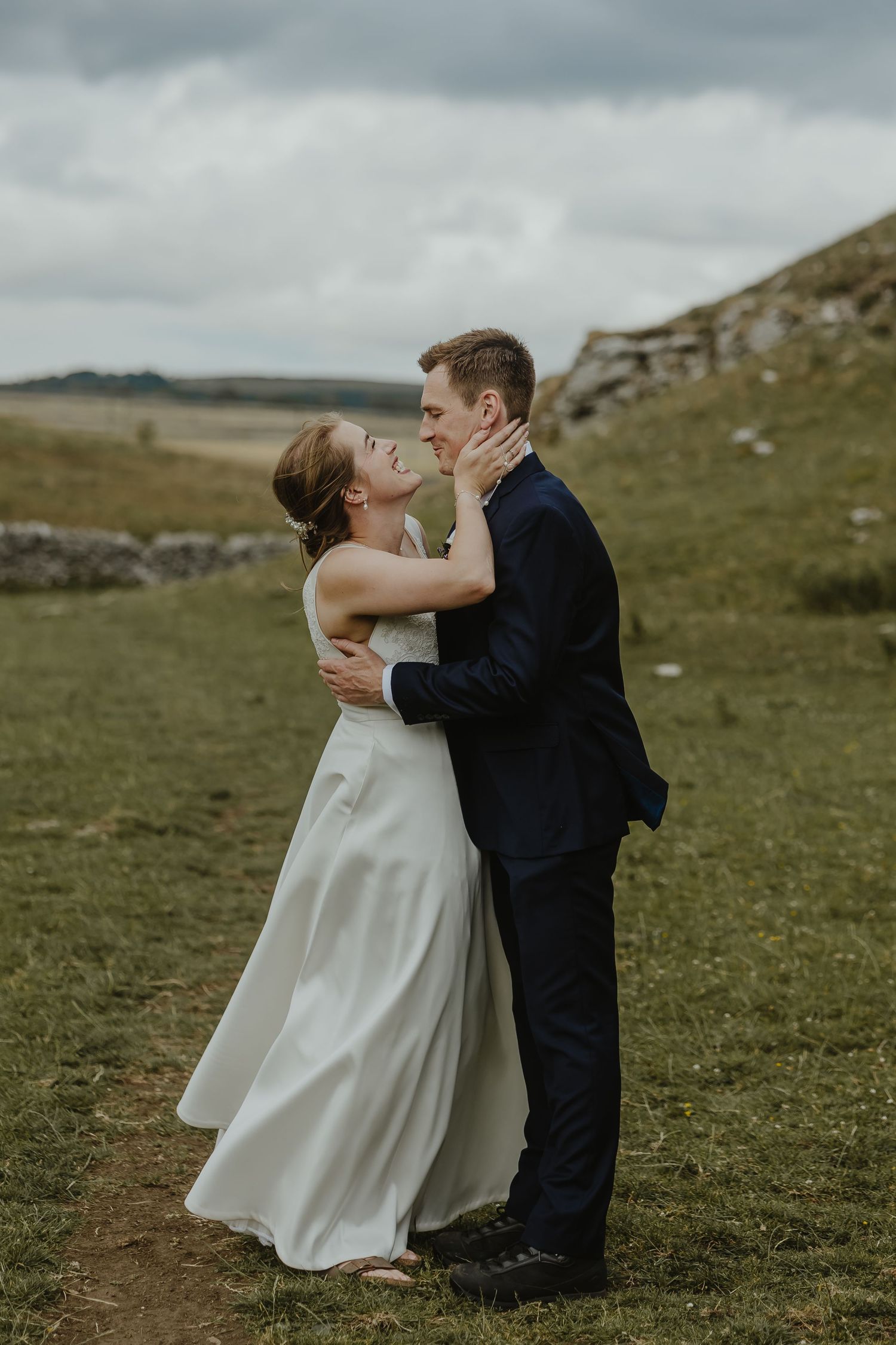 Intimate wedding portrait on windswept hillside.