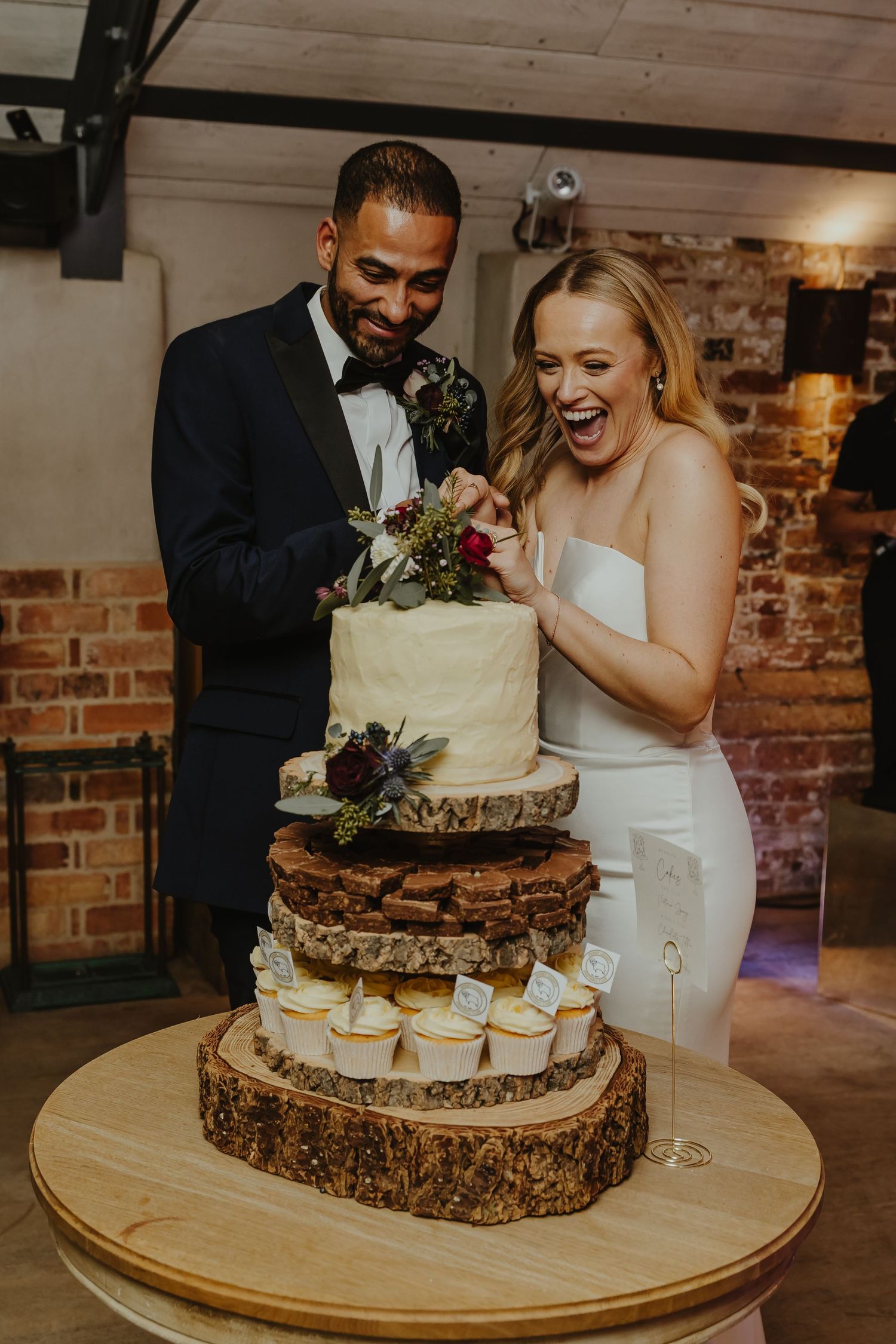 Wedding cake displayed on wooden slices with rustic decorative elements.