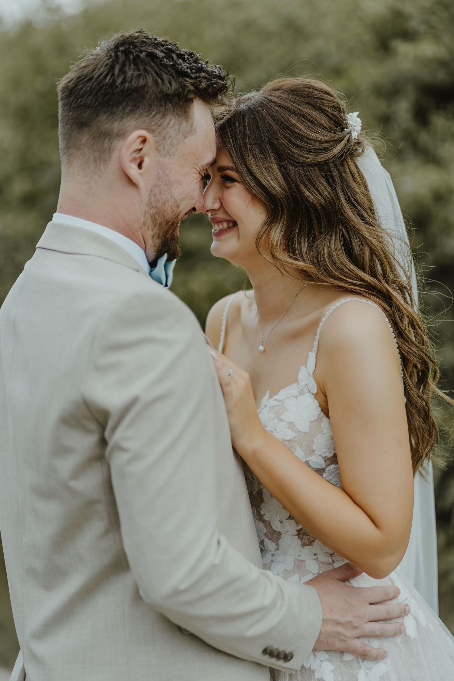 A joyful wedding couple sharing an intimate moment outdoors.