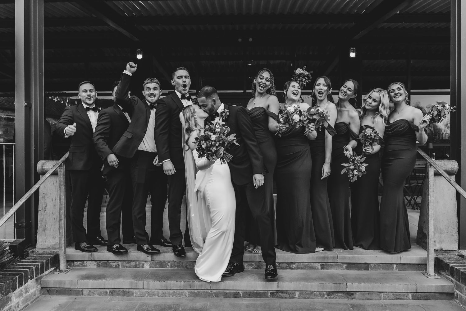 Black and white panoramic shot of wedding party lined up on steps.