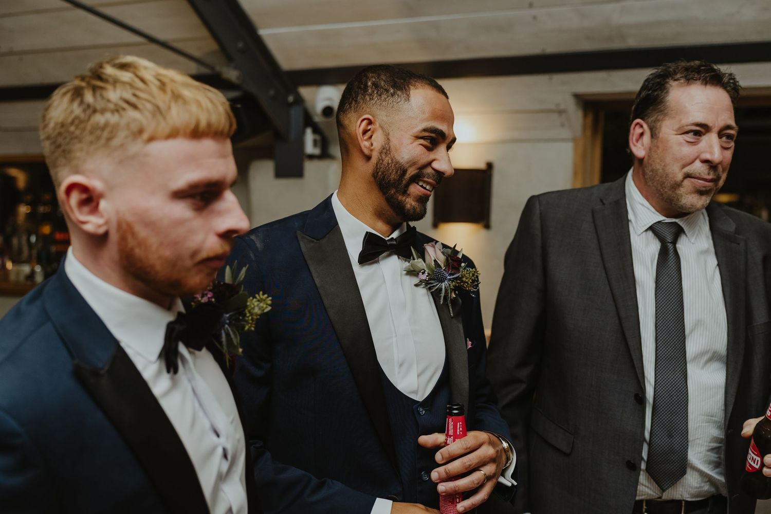 Groomsmen in dark suits gather for candid moment during wedding celebrations.