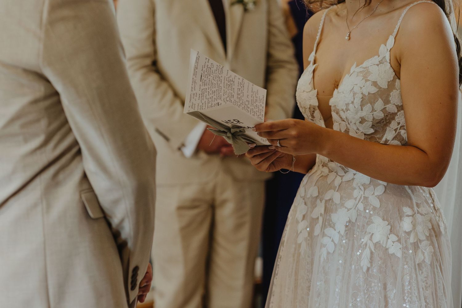 Close-up of hands holding wedding vows written on paper during an intimate ceremony.