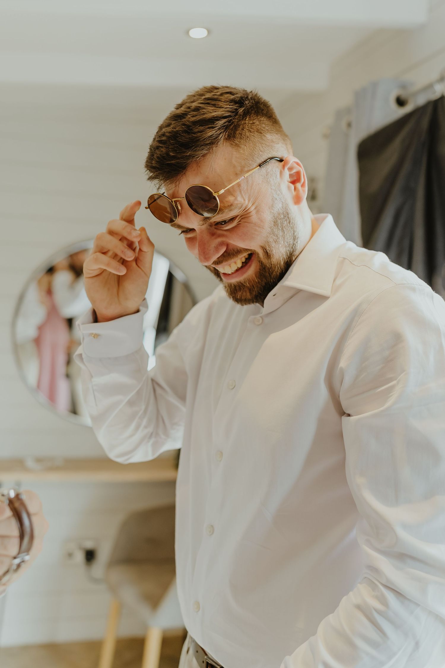 Person in white button-down shirt adjusting collar while getting dressed.