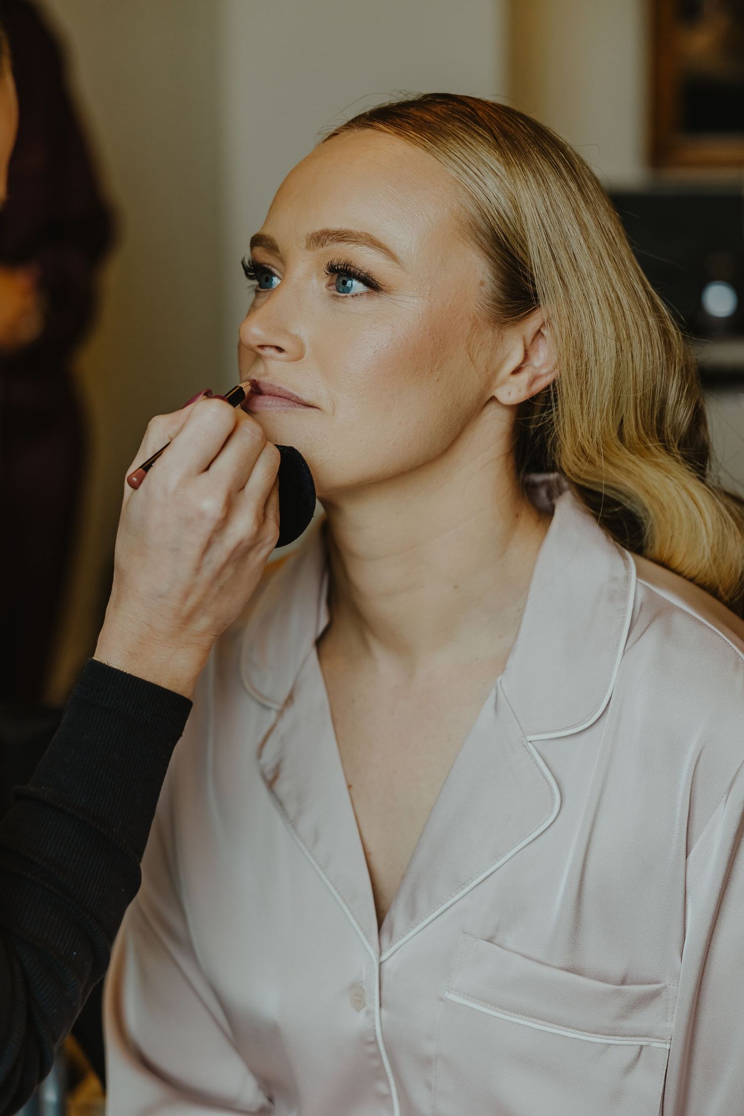 Makeup application in progress during wedding preparations in natural light.