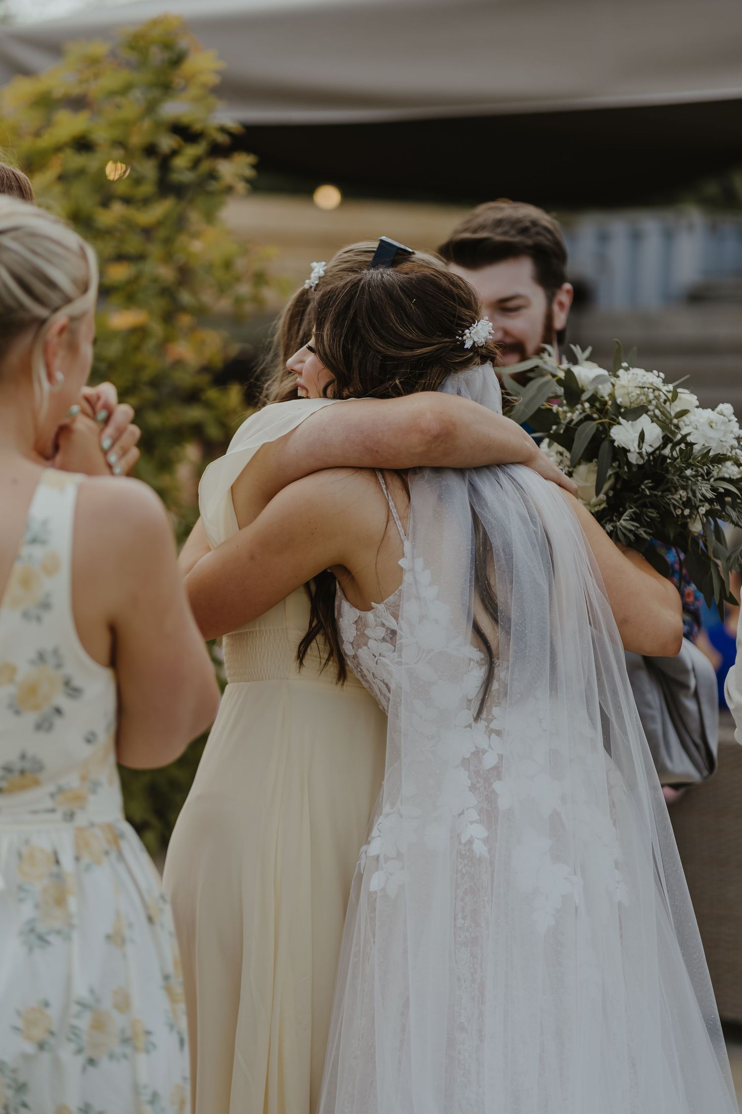 Wedding party members share emotional embraces during celebration.