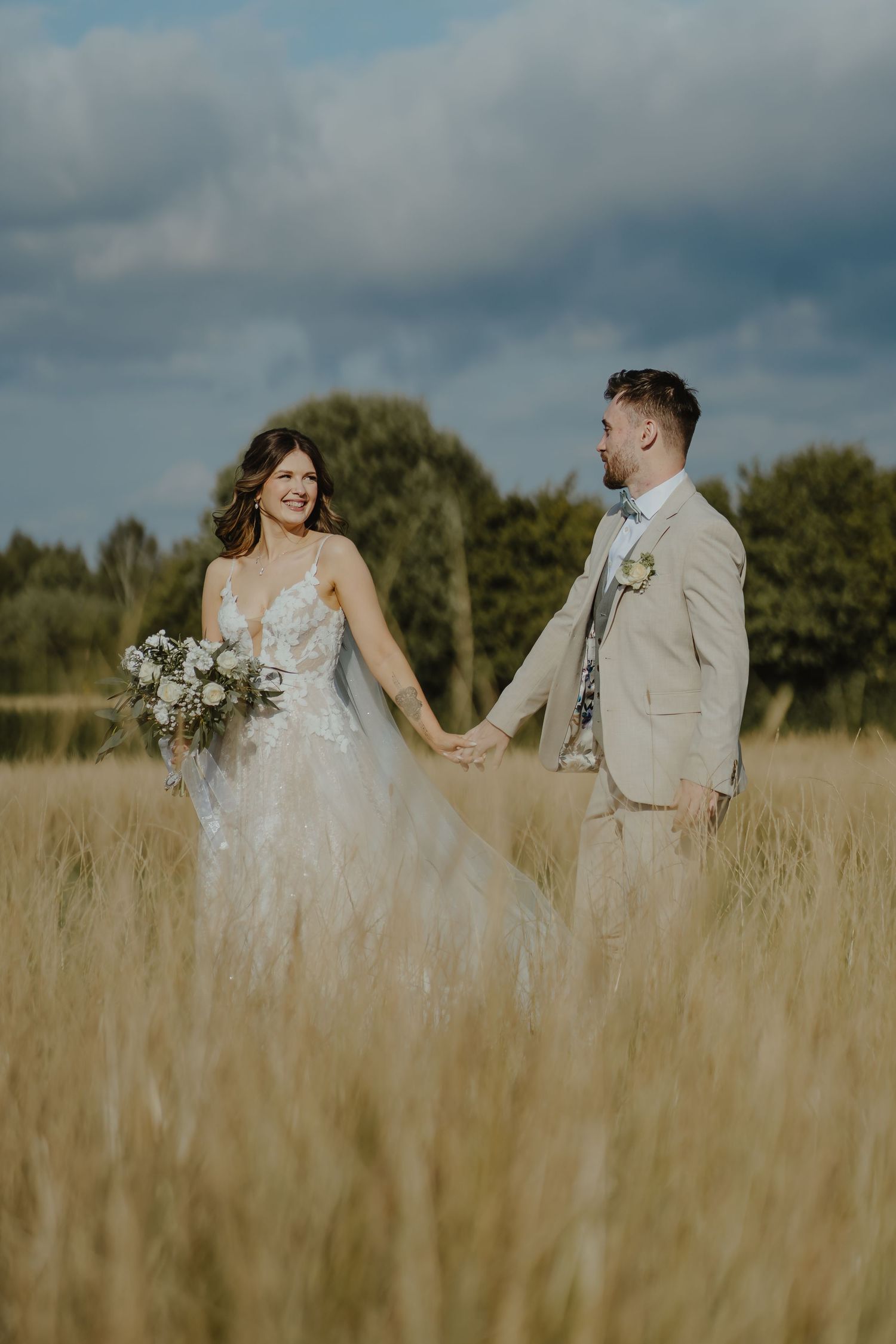 Newlyweds share intimate moment in golden field during sunset.