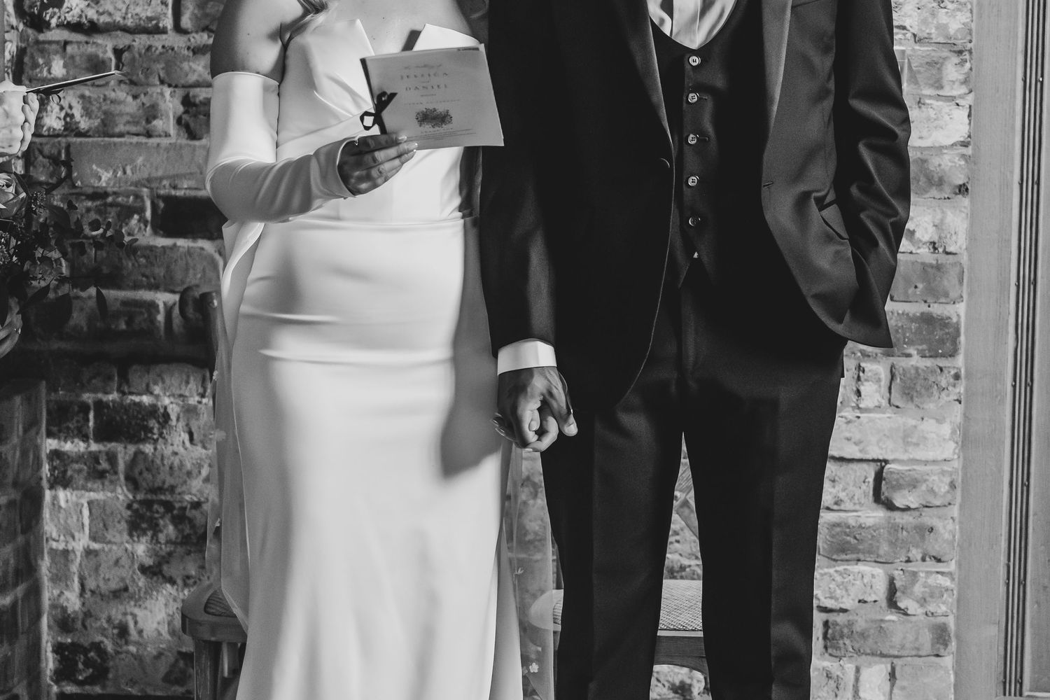 Wedding party gathering in front of exposed brick wall during reception.