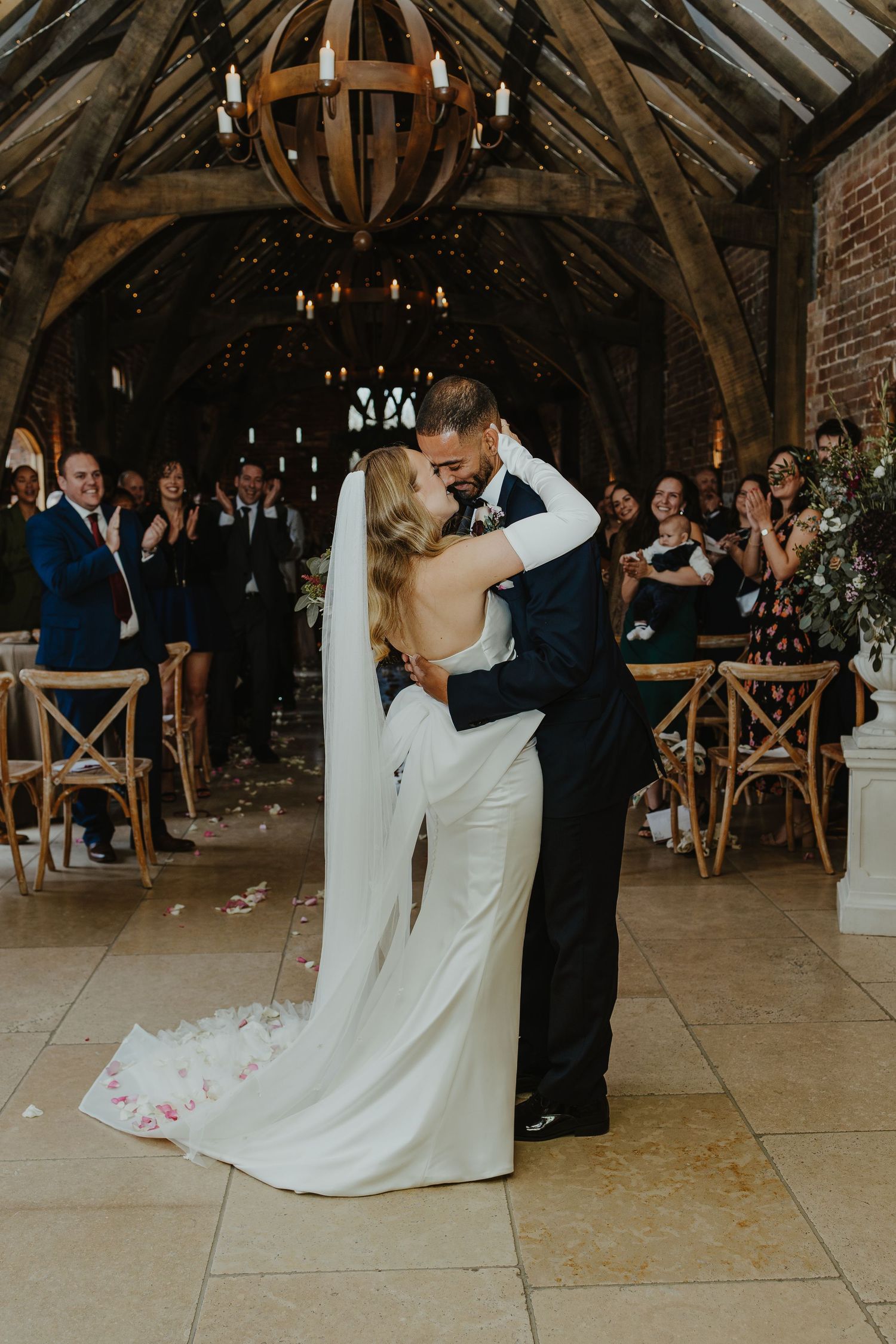 Romantic first dance moment captured in rustic barn wedding venue with wooden architecture.