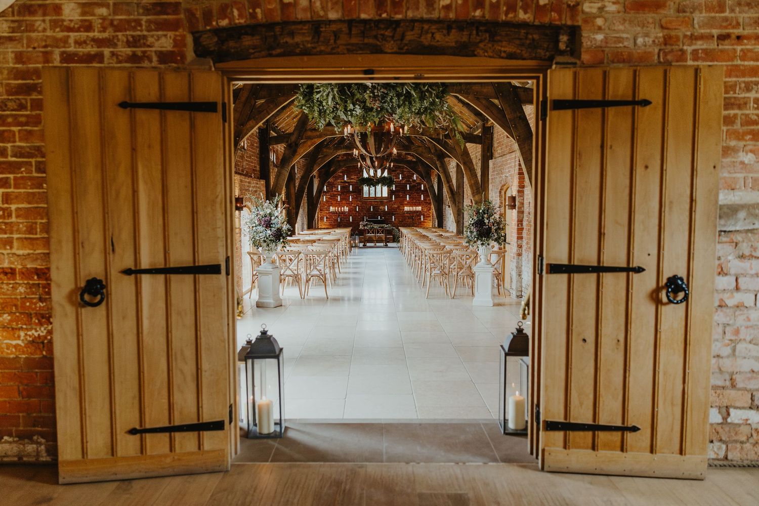 Elegant wooden doors opening to reveal a beautiful barn wedding ceremony setup.