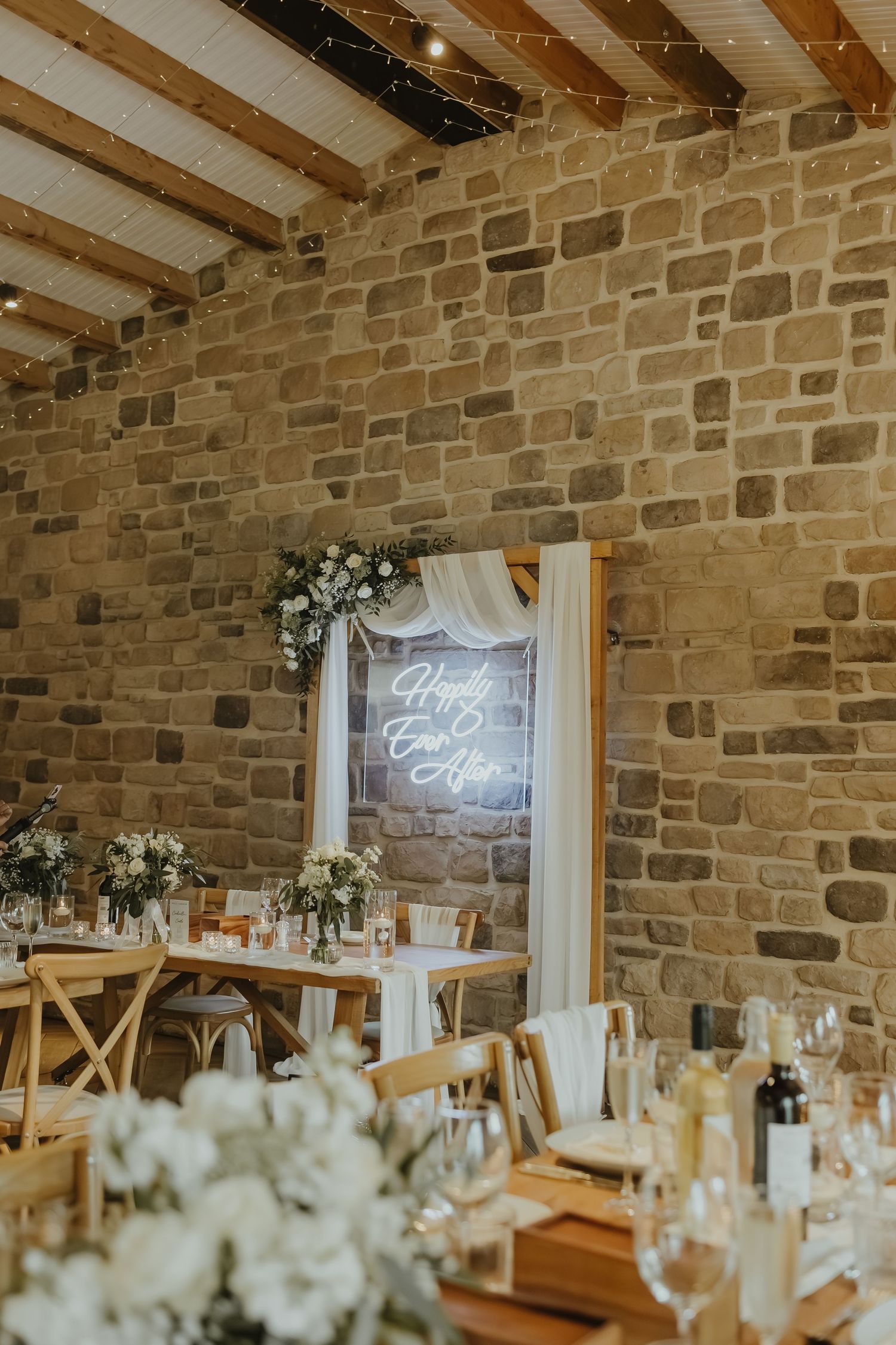 Elegant wedding reception setup with rustic decor, stone walls, and wooden beams.