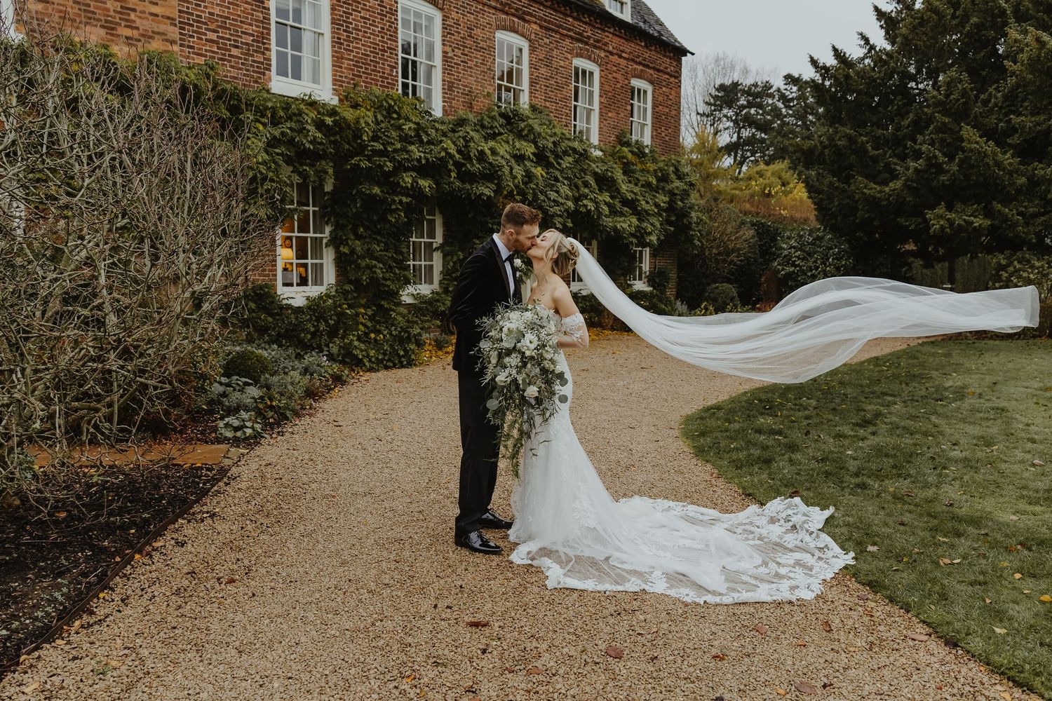 Romantic wedding photos captured on a gravel path near a historic building.