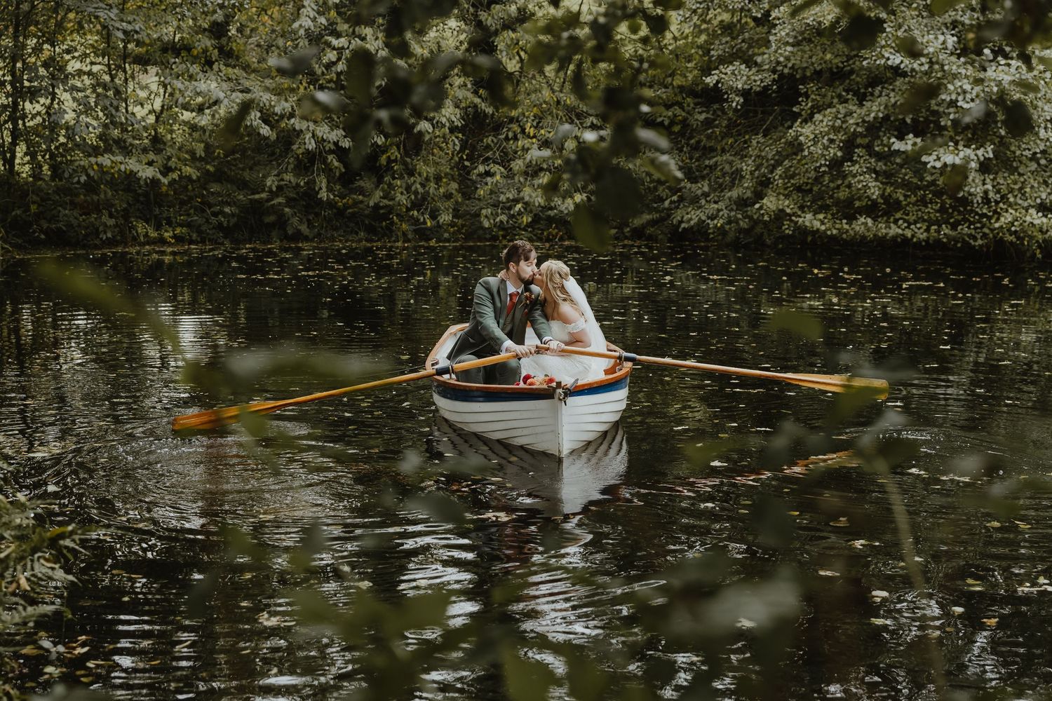 Romantic boat ride on lily pond during wedding photoshoot.