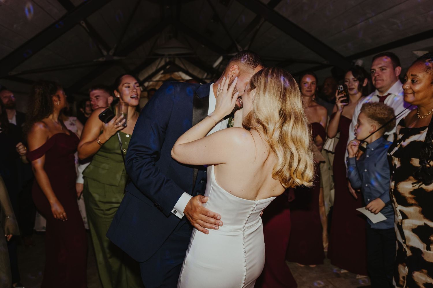 A romantic dance moment captured at a wedding reception with guests watching in the background.