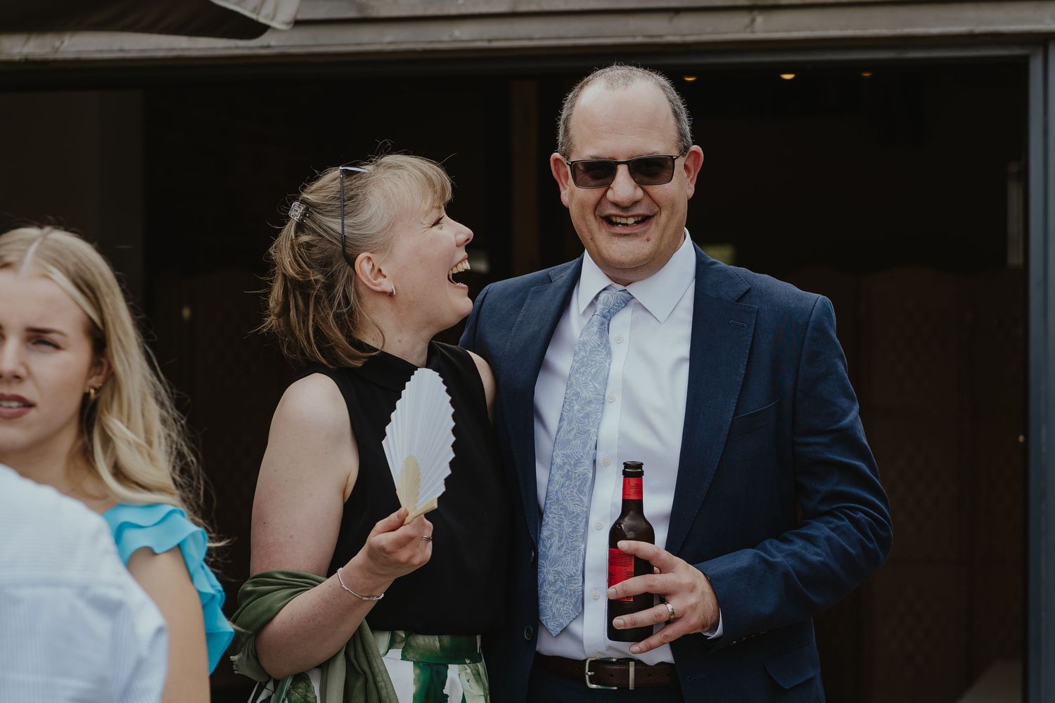 Wedding guests enjoy drinks and conversation at outdoor celebration.
